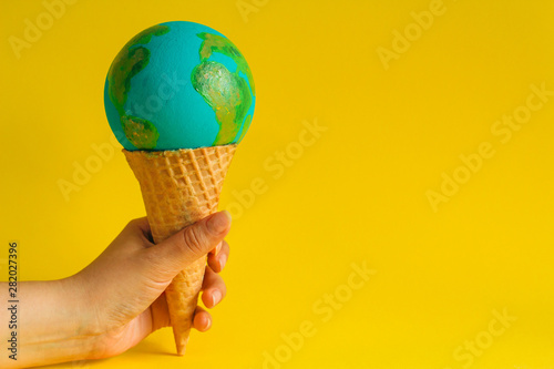 Fototapeta Naklejka Na Ścianę i Meble -  female hand holds waffle cone with Earth model