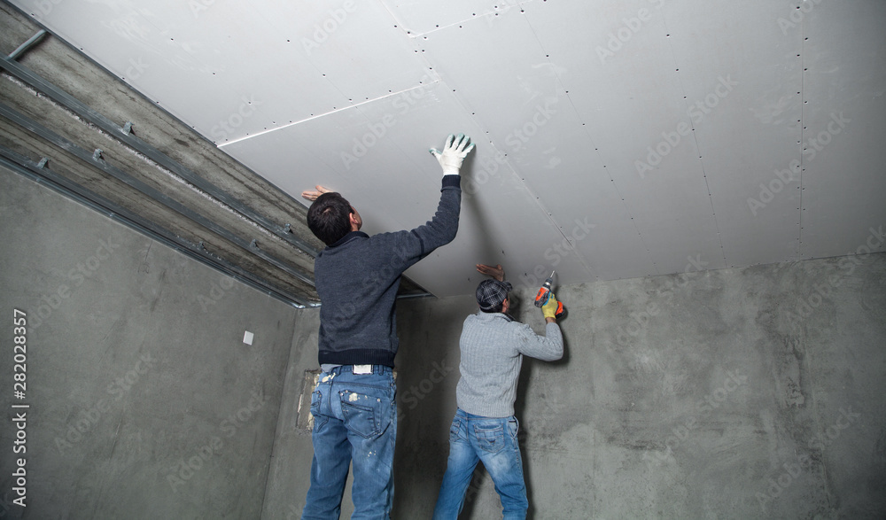 Valokuva Workers fitting panel into frame of ceiling.