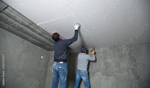 Valokuva Workers fitting panel into frame of ceiling.