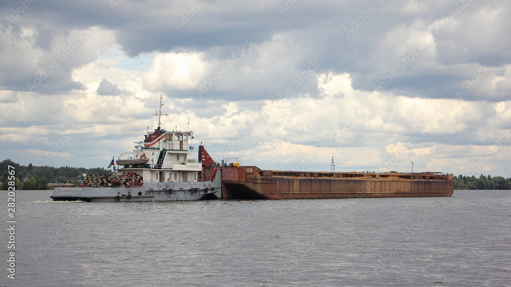 Pusher vessel tugboat carries a empty barge cargo ship for loading on the river, logistics of cargo transportation by water transport