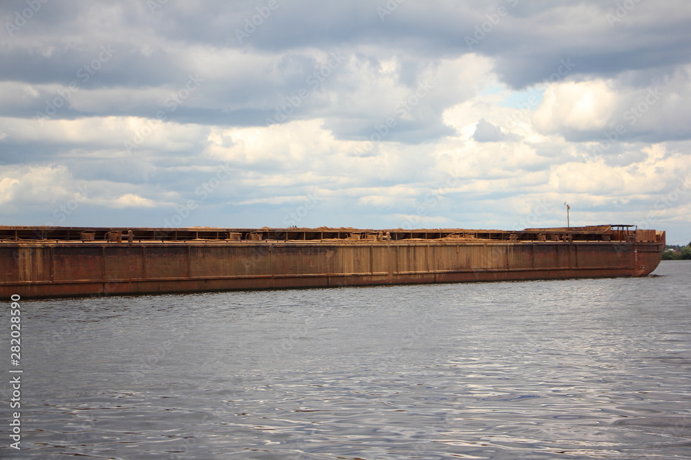 Empty barge on the river close-up, water transportation of bulk materials on river on stormy sky background