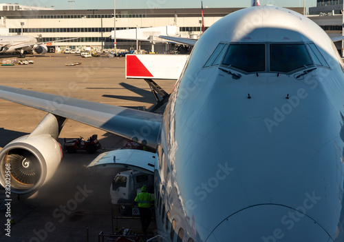 jet aircraft docked at sydney airport , with a person loading good on the plane