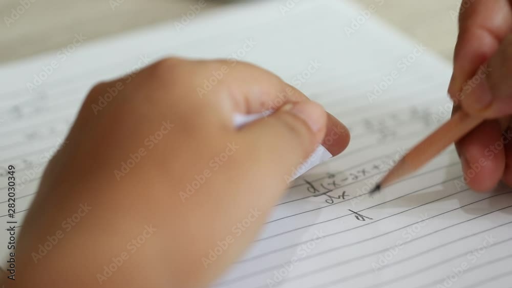 Student using formula math sheet to cheat on test. Hand of university student holding pencil doing math question in examination and cheating in test with answer piece of paper in hand. 