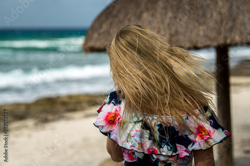 Blonde hair girl from the back with blowing hair in colorful shirt in the Caribbean photo