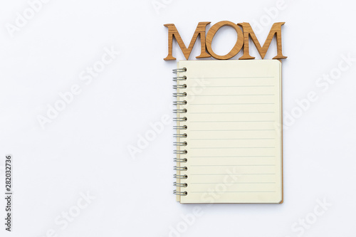 Mom wooden letter on Blank yellow lined note book isolate on white background, stationary object photo