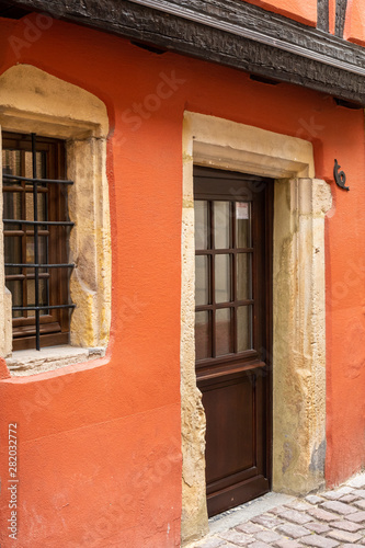 Traditional entrance door and wooden window with metal grill in Colmar, France