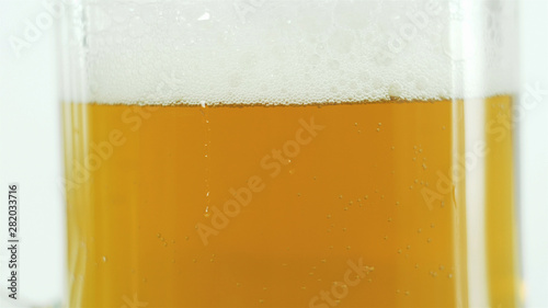 beer in a large class glass, light beer with thick white froth.