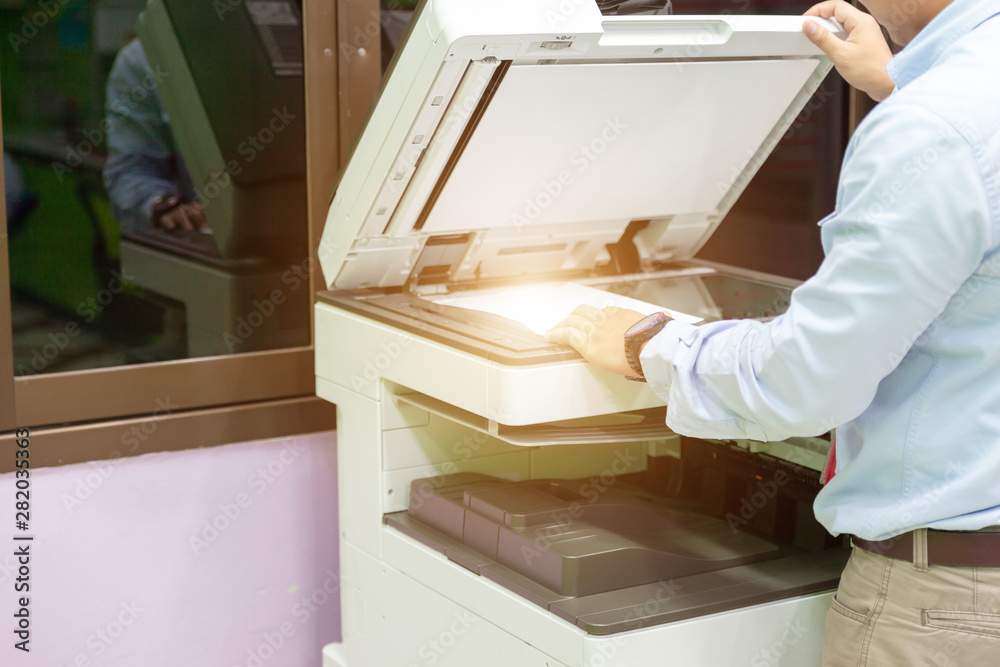 Men press the button of the copier. Man copying paper from Photocopier