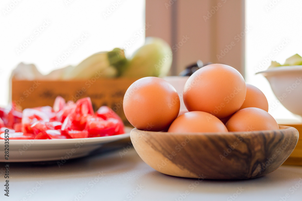Plates with sliced vegetables and eggs with olives in bowls on kitchen table, cooking process concept Plates with sliced vegetables and eggs with olives in bowls on kitchen table, cooking process concept
