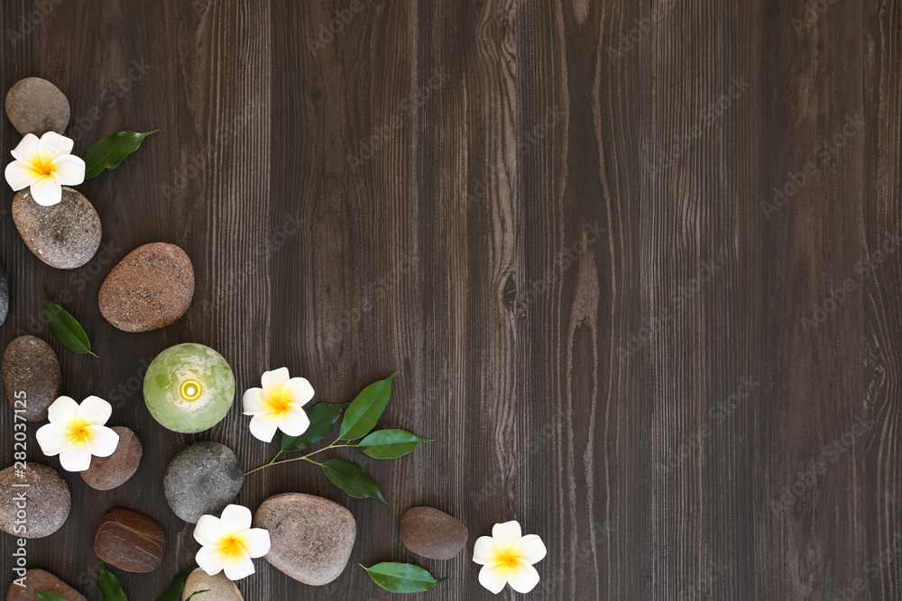 Obraz premium Flat lay composition with spa stones, flowers and candle on wooden background. Space for text