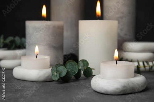 Composition with burning candles, spa stones and eucalyptus on grey table