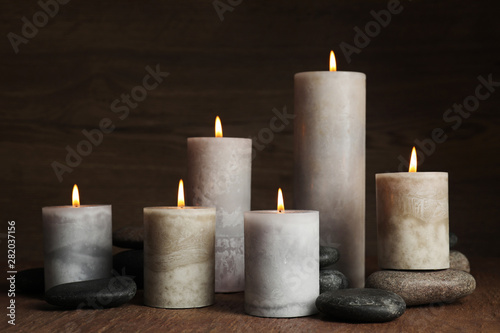 Burning candles and spa stones on wooden table