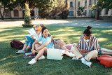 Friendly students sitting together on the grass after classes.