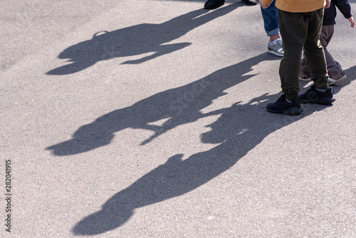 Shadows and Silhouettes of three Children playing in a Street on surface of asphalt Road as Background or Texture