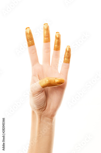 Hands in gold paint. Golden fingers. Female hand is showing numbers isolated on white background. Sign language. Hand numbers