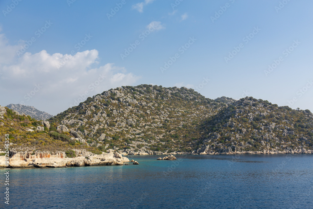 Mediterranean sea overlooking the mountains. Aerial top view of sea waves hitting rocks on the beach with turquoise sea water. Amazing rock cliff seascape in the coastline.