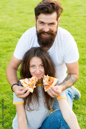 Which is your favorite. Fast food. Bearded man feeding woman cheesy pizza. Couple in love dating outdoors eat pizza. Hungry students sharing food. Couple eating pizza relaxing on lawn. Family weekend