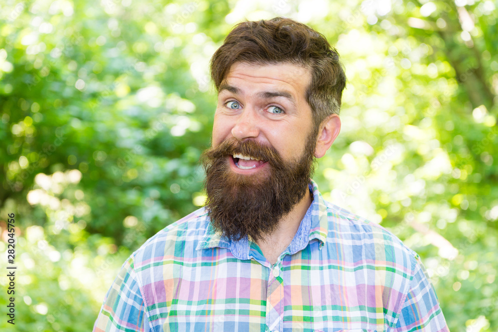 Fototapeta premium Summer vacation concept. Man bearded hipster green trees background. Hike and travel. Guy relax in summer nature. United with environment. Handsome lumberjack. Man beard and mustache in summer forest