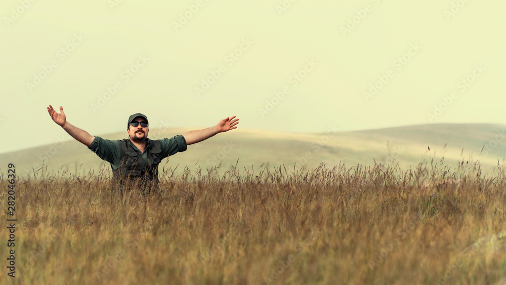 happy and free man sitting on yellowed field with open arms happy and free man sitting on yellowed field with open arms