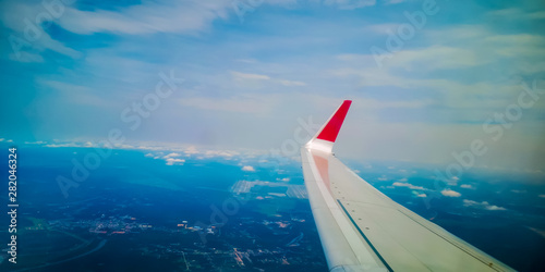 Airplane wing over the sky background, view from window