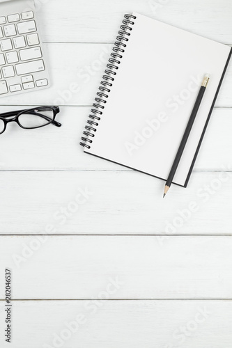 Top view of minimal office desk with an open blank notebook and stationery items