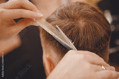 Barber master hairdresser does hairstyle with scissors and comb. Concept Barbershop