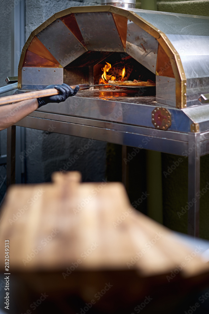 The baker shows a freshly baked focaccia, on the peel. The baker shows a freshly baked focaccia, on the peel.