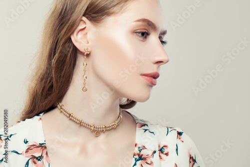 Fotobehang Elegant woman with fashion golden chain earrings and pearls necklace on white ba