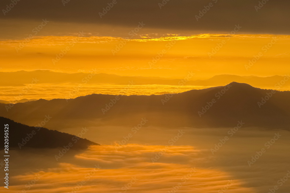 Mountain view misty morning of top hills around with sea of mist in valley and yellow sun light with cloudy sky background, sunrise at Pha Tang, Chiang Rai, northern of Thailand. Mountain view misty morning of top hills around with sea of mist in valley and yellow sun light with cloudy sky background, sunrise at Pha Tang, Chiang Rai, northern of Thailand.