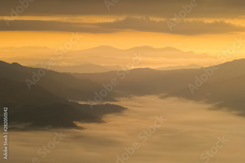 Mountain view misty morning of top hills around with sea of mist in valley and yellow sun light with cloudy sky background, sunrise at Pha Tang, Chiang Rai, northern of Thailand. © Yuttana Joe