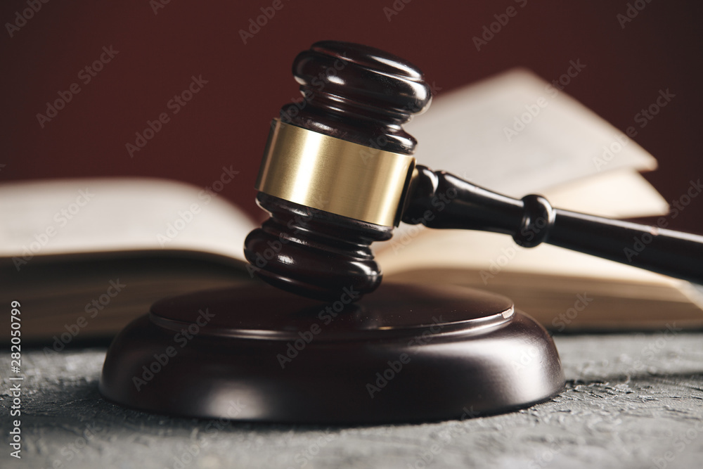 Law concept - Open law book with a wooden judges gavel on table in a courtroom or law enforcement office on black background. Law concept - Open law book with a wooden judges gavel on table in a courtroom or law enforcement office on black background.