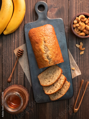 Homemade banana bread pound sliced with cashew nuts and honey on wooden table.