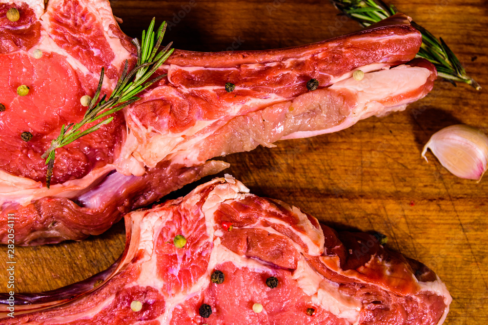 Raw ribeye steak, spices, rosemary and garlic on cutting board. Top view Raw ribeye steak, spices, rosemary and garlic on cutting board. Top view