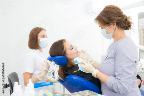 a woman dentist with an assistant treats a tooth to a woman in a modern dental clinic