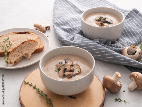 Mushroom cream soup in white bowl with bread on the table. Delicious cream soup with champignon mushrooms.
