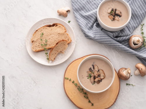 Mushroom cream soup in white bowl with bread on the table. Delicious cream soup with champignon mushrooms.