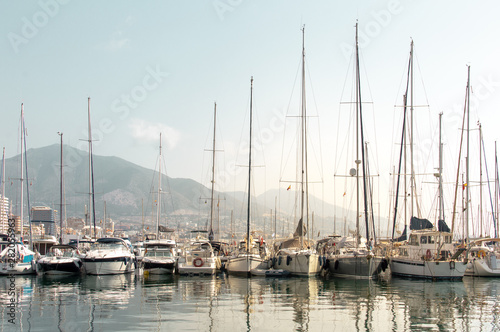 Sailboats and yachts in the dock reflected in the water with the city and mountains in the background. Landscape of Costa del Sol  Fuengirola   Spain.