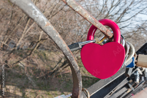 big purple heart shaped love padlock hanging on lovers bridge. Conceptual symbol of unbreakable love and unity of a couple. purple love padlock with copy space for text on it.