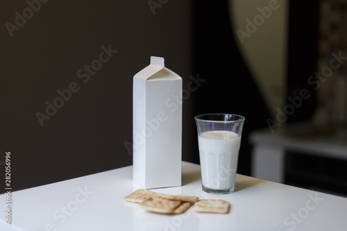 Carton box and glass of milk on table in kitchen