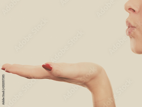 Blonde woman sending air kiss on palm hand photo