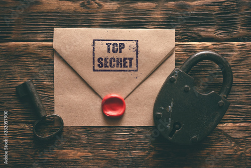 Top secret documents in envelope, rusty padlock and a key on a wooden table flat lay background. Confidential information concept. photo