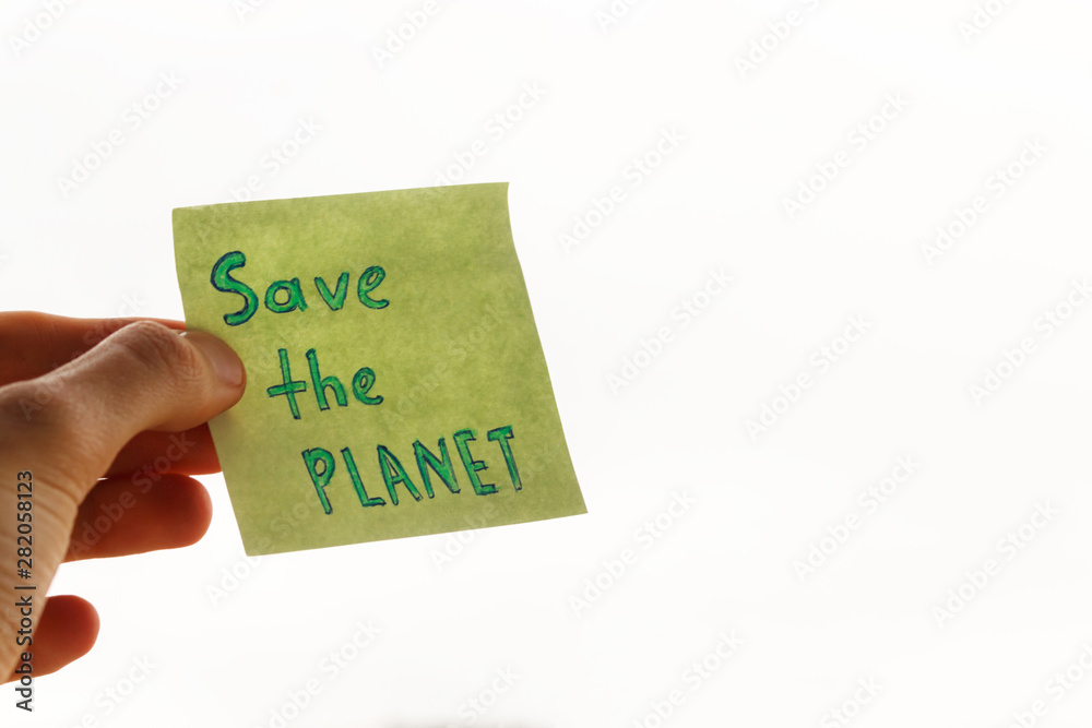 an appeal to save the planet earth is written on a piece of paper, white sky in background. handwritten inscription save the planet on a square piece of paper in the male hand. an appeal to save the planet earth is written on a piece of paper, white sky in background. handwritten inscription save the planet on a square piece of paper in the male hand.