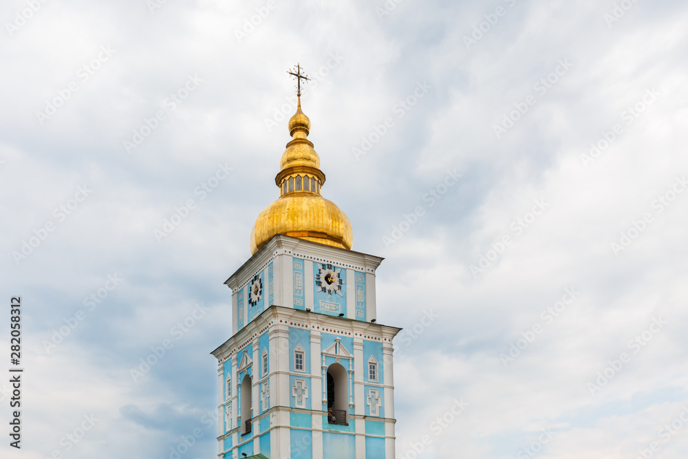 The bell tower of Saint Michael's Golden-Domed Monastery on the background of gray sky with clouds.
