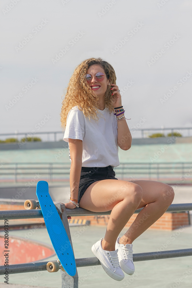 Young girl sitting on a railing with a skateboard