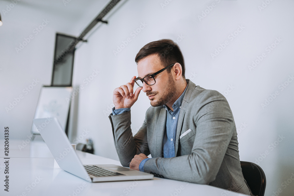 Bearded man in a suit works behind the laptop sitting in a comfy Bearded man in a suit works behind the laptop sitting in a comfy