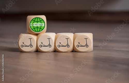 Cubes and dice with e-mobility and e-scooter on wooden background