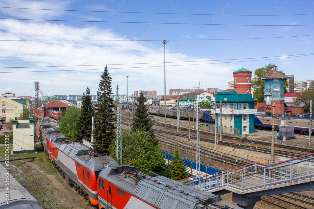 railway station with a lot of rail tracks and the composition of the train with cars on the background of the modern city, aerial view railway station with a lot of rail tracks and the composition of the train with cars on the background of the modern city, aerial view