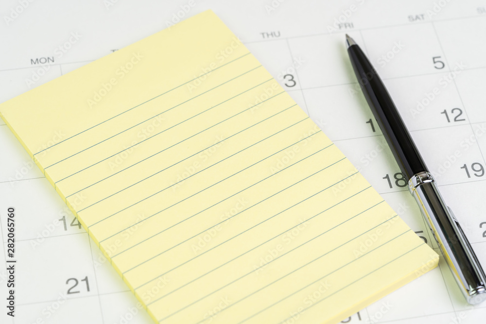 Yellow notepad with pen on white clean calendar with date number using as important appointment, event, reservation and business planning concept