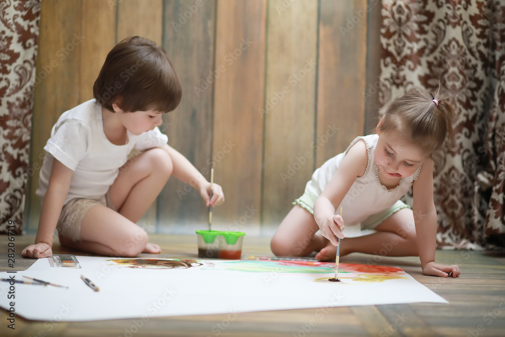 Little children paint on a large sheet of paper Little children paint on a large sheet of paper