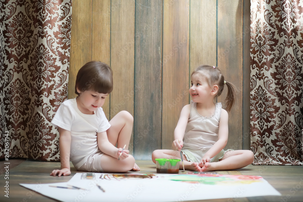 Little children paint on a large sheet of paper Little children paint on a large sheet of paper